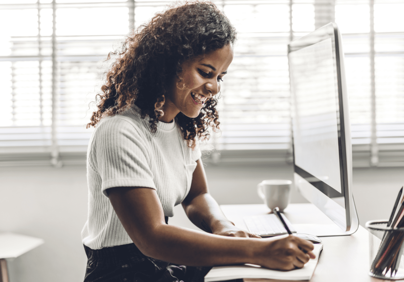 A woman sitting at her desk writing on paper.