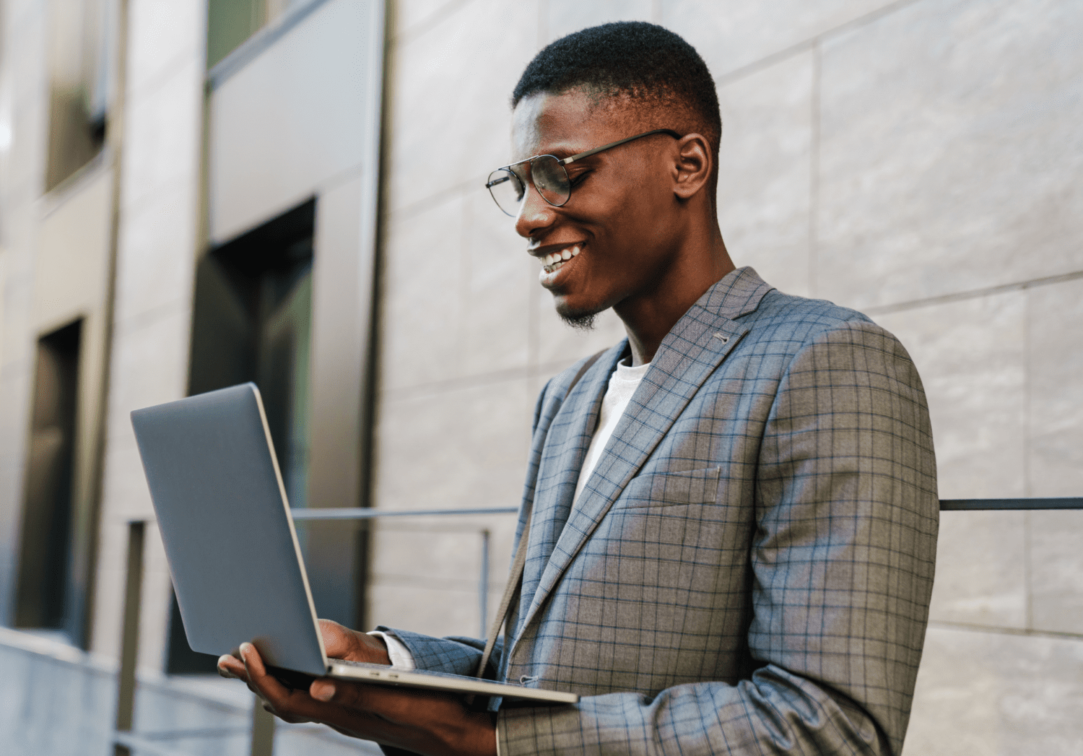 A man in a suit and glasses is holding a laptop