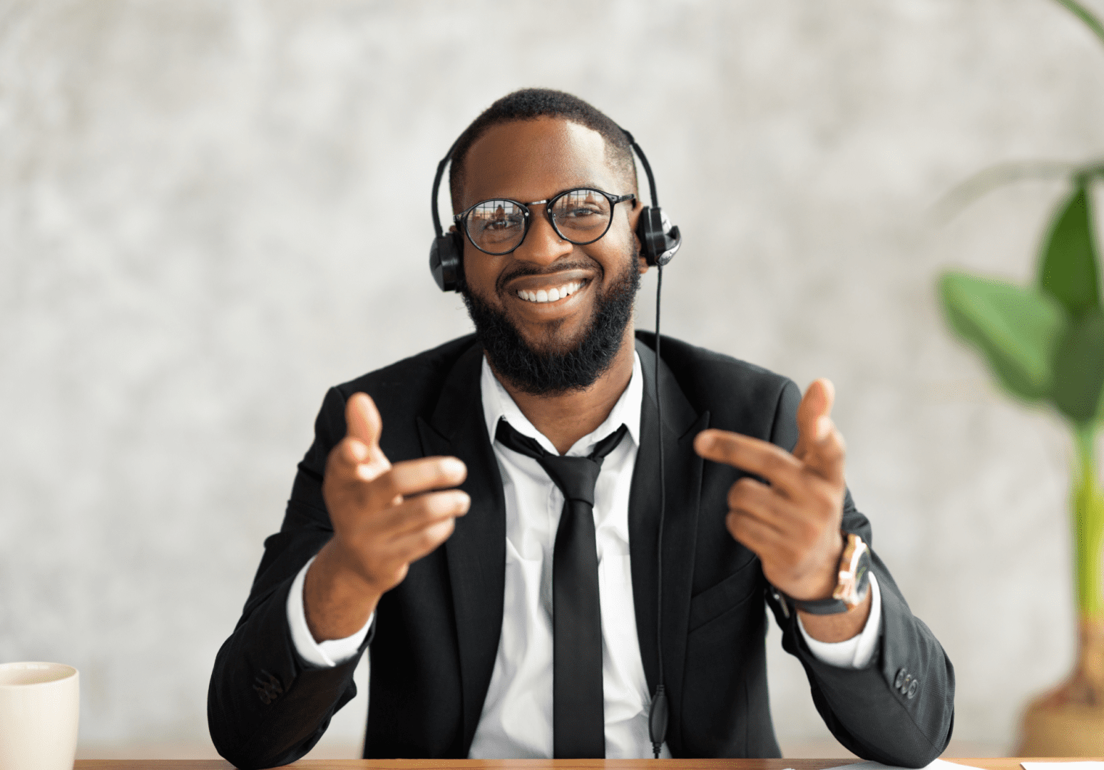 A man wearing headphones and glasses sitting at a table.